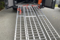 Loading ramps rest on vehicle with red straps