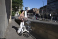 Lady walking down street with four wheeled rollator with bag