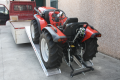 Tractor driving up vehicle ramps onto van 