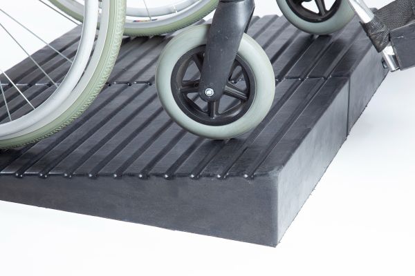 Manual wheelchair going up rubber threshold ramp