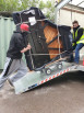 Two men loading piano into van using van loading ramp 