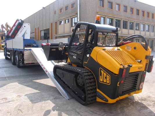 Skid steer loading driving on to loading ramps 