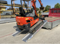 Tractor driving up vehicle ramps onto flat bed van 