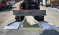 Digger driving up pair of loading ramps onto vehicle 