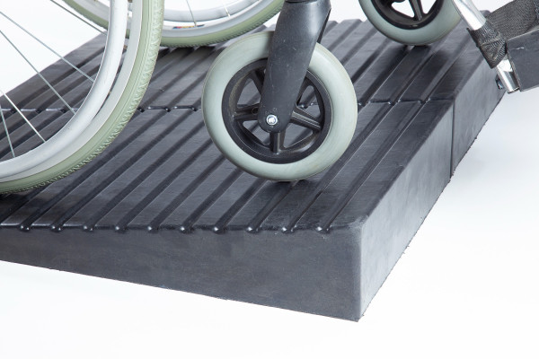 Manual wheelchair going up rubber threshold ramp