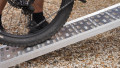 Motorbike loading ramp resting on boot of car with bike being loaded, close up of surface