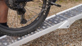 Motorbike loading ramp resting on boot of car with bike being loaded