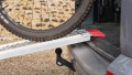 Motorbike loading ramp resting on boot of car with bike being loaded