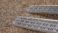 Pair of motorbike loading ramps resting on vehicle boot, close up of foot end