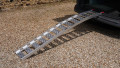 Single aluminium lightweight motorcycle ramp resting on the boot of a vehicle