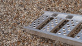 Single aluminium lightweight motorcycle ramp resting on the boot of a vehicle, close up of the foot end of the ramp