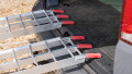 pair of motorbike ramps with support legs resting on the back of a vehicle, close up of red, finger style rest on connections