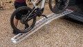 Single motorbike ramp with support legs resting on a vehicle with a push bike being loaded