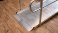 Close up of the foot end of a wheelchair ramp with handrails