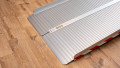 Extra wide wheelchair ramp resting on a step. Close up view of the foot end of the mobility aid ramp