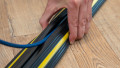 Hand placing a cable into a single channel black and yellow cable protector