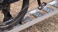Single aluminium lightweight motorcycle ramp resting on the boot of a vehicle with a push bike being pushed up, close up of the grip surface