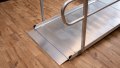 Close up of the foot end of a wheelchair ramp with handrails