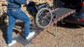 manual wheelchair being pushed up a rollable ramp into the boot of a car