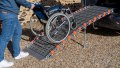 manual wheelchair being pushed up a rollable ramp into the boot of a car