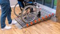 Manual wheelchair on a portable aluminium wheelchair ramp