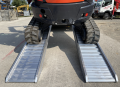 Digger driving up pair of loading ramps