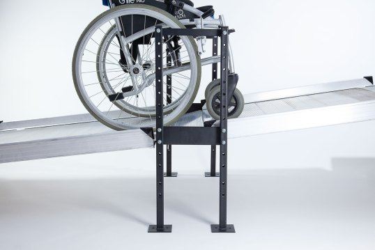 Wheelchair going up two ramps connected by black joining support