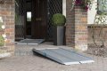 Premium folding wheelchair ramp with anti-slip surface resting on a step in front of a house
