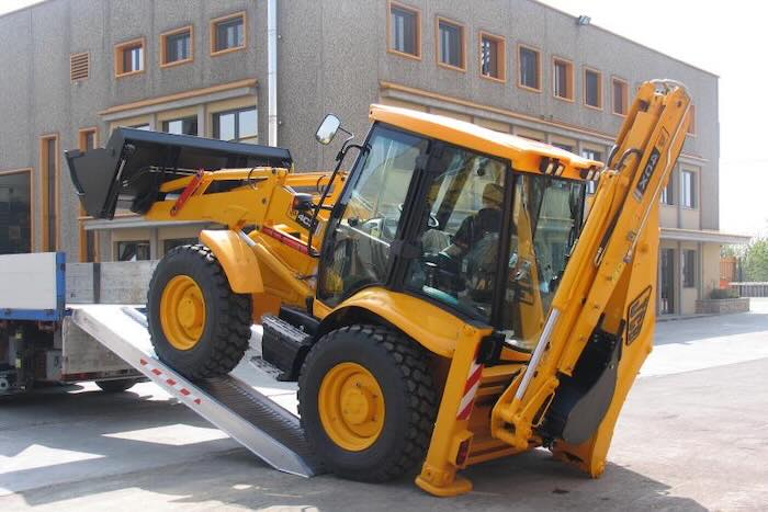 Rubber tracked machine driving up pair of aluminium loading ramps Rubber tracked machine driving up pair of aluminium loading ramps into flat bed vehicle