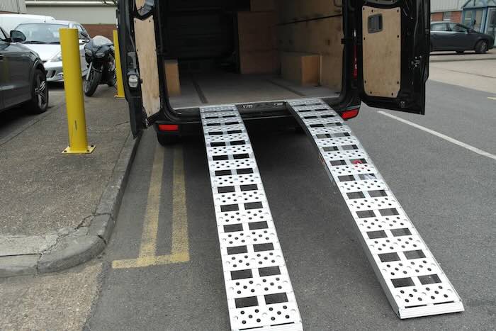 Pair of curved aluminium loading ramps resting on van 