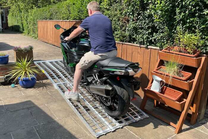 Man sat on bike going up a motorcycle ramp kit over steps