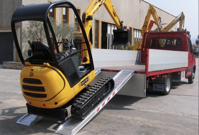Rubber tracked machine driving up pair of aluminium loading ramps Rubber tracked machine driving up pair of aluminium loading ramps