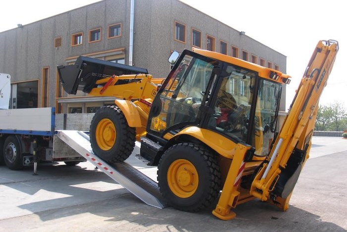 Rubber tracked machine driving up pair of aluminium loading ramps Rubber tracked machine driving up pair of aluminium loading ramps