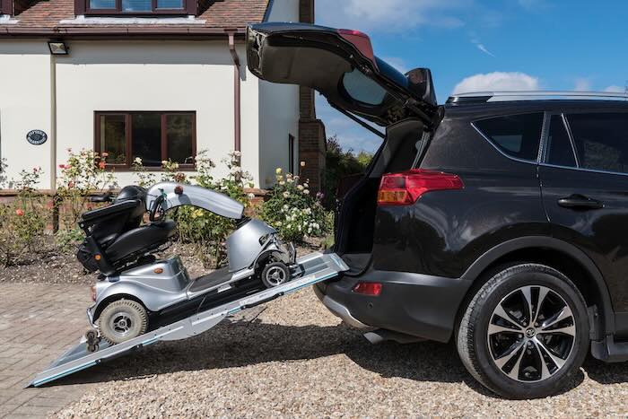 Mobility scooter being loaded into car boot using a ramp