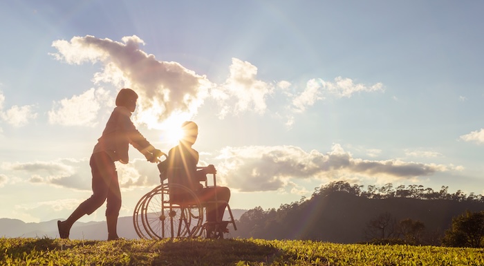 Individual pushing a wheelchair with a scenic background Individual pushing a wheelchair with a scenic background