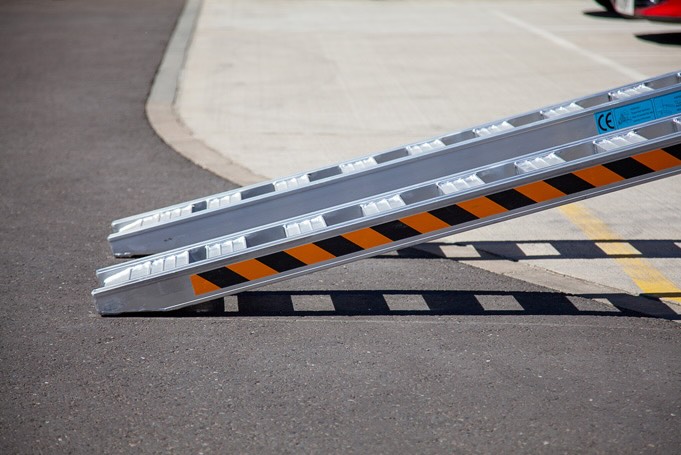 Rubber tracked machine driving up pair of aluminium loading ramps Rubber tracked machine driving up pair of aluminium loading ramps