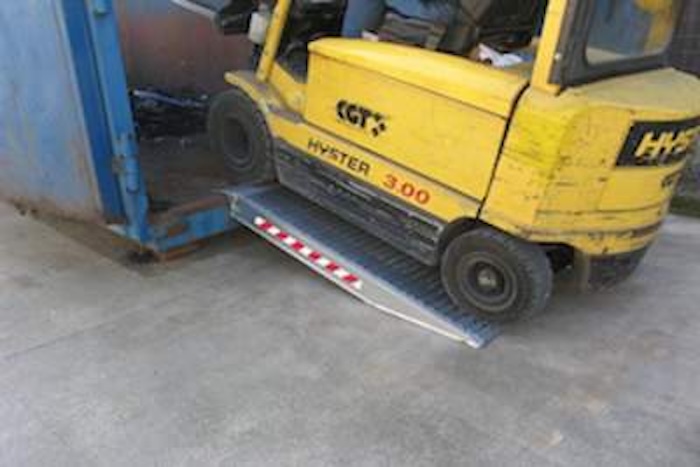Forklift driving up a pair of aluminium container ramps 