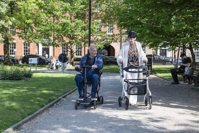 Lady walking with all-terrain rollator in park Lady walking with all-terrain rollator in park