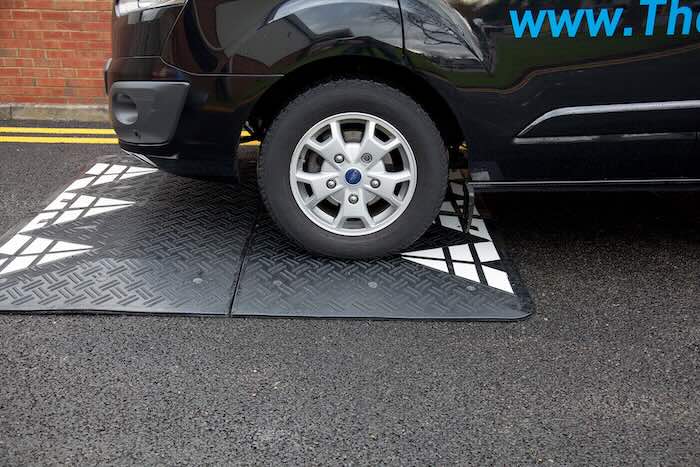 Van driving over black speed cushion Van driving over black speed cushion on tarmac road