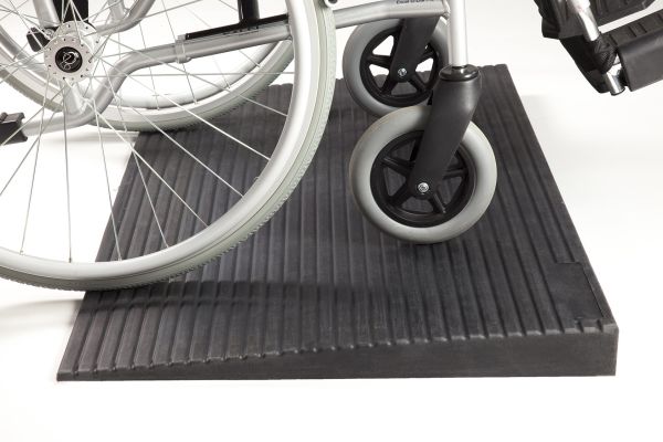 Manual wheelchair going up rubber threshold ramp