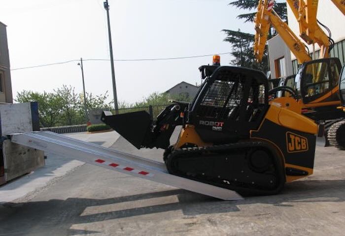 Rubber tracked machine driving up pair of aluminium loading ramps Rubber tracked machine driving up pair of aluminium loading ramps