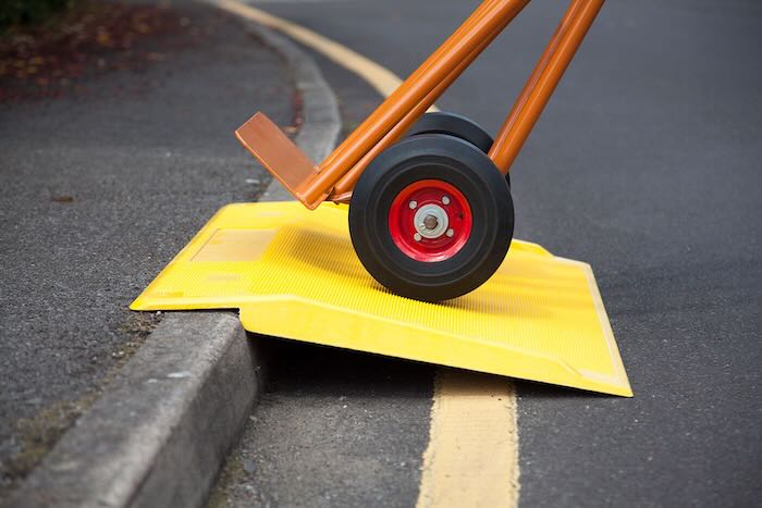 Trolley going up kerb using a yellow kerbhopper ramp