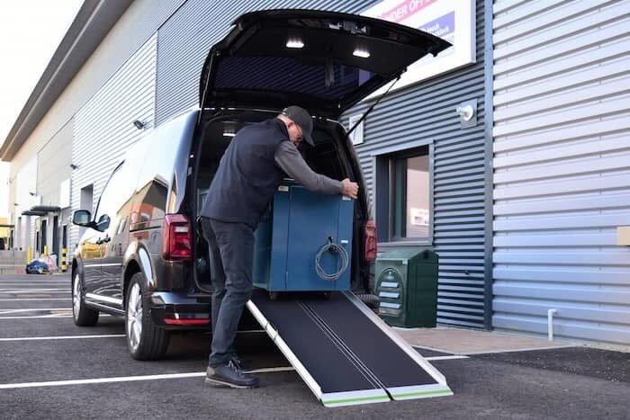 Man loading goods out of car down ramp