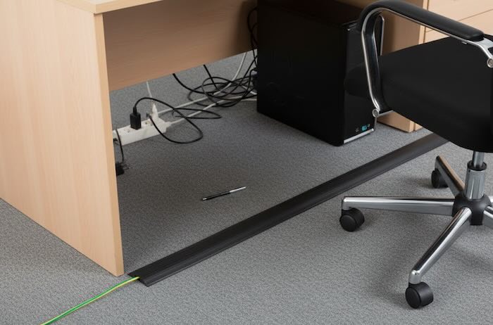 Black floor cable protector in office infront of desk 