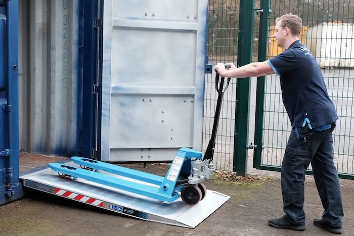 Man pushing pallet truck up ramp into a container Man pushing pallet truck up ramp into a container