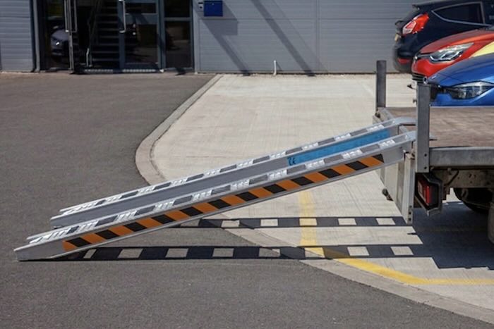 Rubber tracked machine driving up pair of aluminium loading ramps Rubber tracked machine driving up pair of aluminium loading ramps