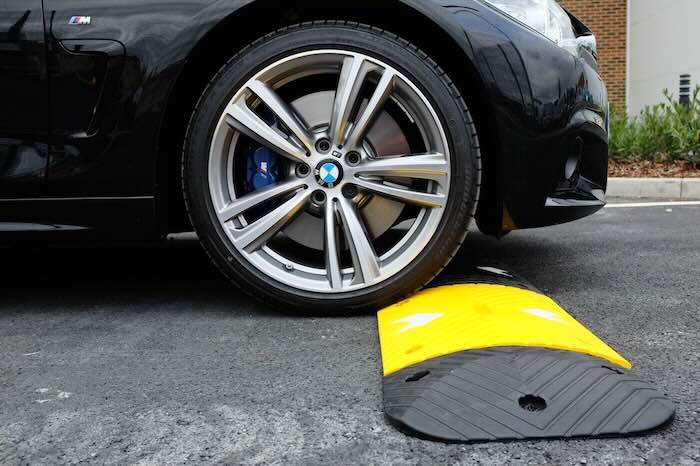 Car driving over rubber speed bump on tarmac road Car driving over rubber speed bump on tarmac road