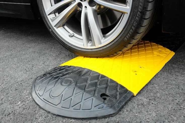 BMW driving over black and yellow speed ramp BMW driving over black and yellow speed ramp