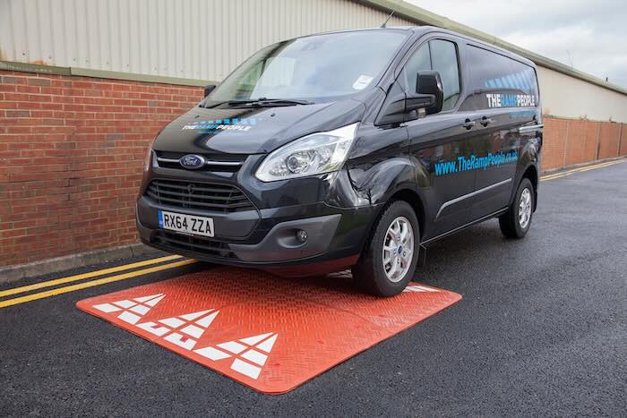 Van driving over red speed cushion Van driving over red speed cushion on tarmac road