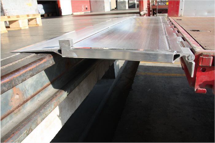 Hinged tailboard bridging gap from vehicle to loading bay 